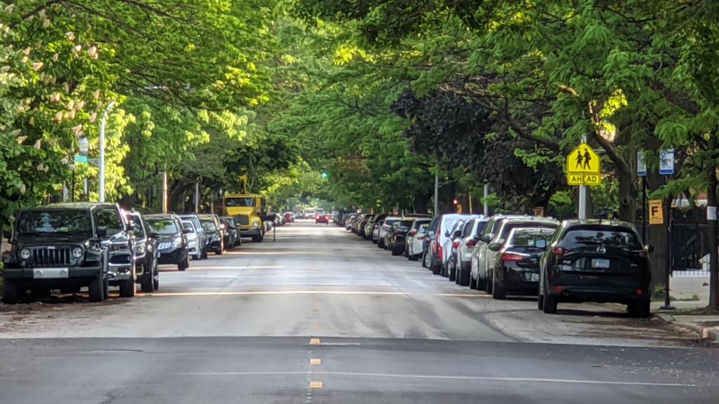 Photo showing a road with parked cars either side and street trees